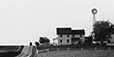 George Tice<br><em>Buggy and Farmhouse with Windmill, Lancaster, PA</em>, 1965</br>Gelatin silver print<br>Image: 10 x 19 1/2"; Mount: 22 x 28"     